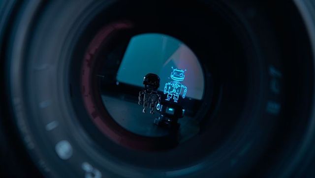 Macro inside camera lens revealing metallic robot figurines with cyan hologram projection