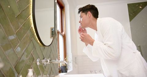 man inspecting hair and skin in stylish bathroom for self-care routine - Download Free Stock Images Pikwizard.com