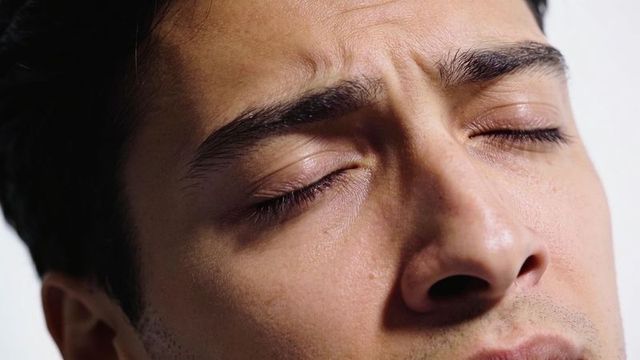 Close-up male headshot showing closed eyes furrowed brow textured skin conveying intensity