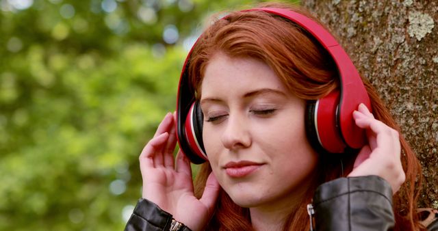 Pretty redhead listening to music in the park on a sunny day - Download Free Stock Photos Pikwizard.com