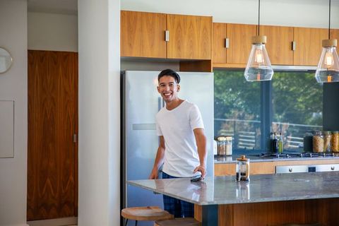 Smiling Man Checking Smartphone in Modern Kitchen Interior