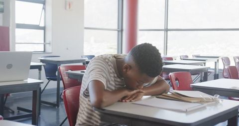 Stressed teenager overwhelmed with schoolwork in classroom