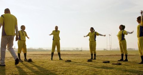 Softball Team Stretching with Coach on Sunrise Field