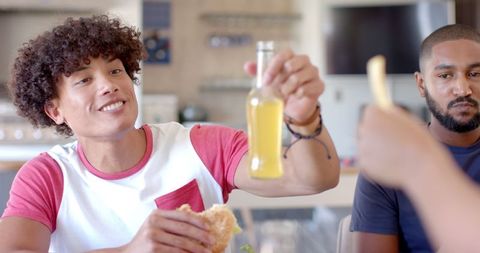 Friends enjoying indoor meal with drinks and sandwiches