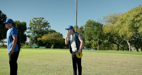 Coach whistling and directing players during outdoor fitness drill with disc and cones