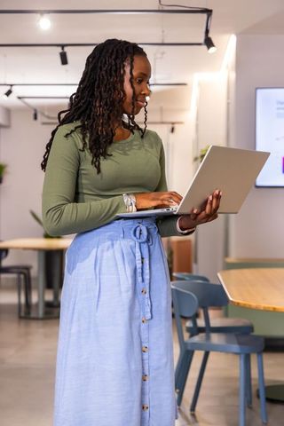 African american woman working on laptop in modern coworking lounge professional casual