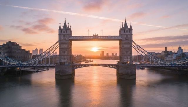 Sunrise reflecting under tower bridge london, twin towers glowing over river thames