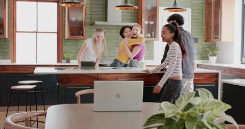 Diverse friends laughing and hugging around sunlit modern-rustic kitchen island gathering