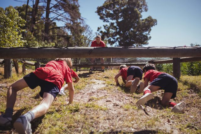 Kids crawling under the net during obstacle course training in the boot camp