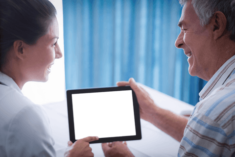 Doctor Holding Transparent Tablet with Senior Patient Smiling at Clinic
