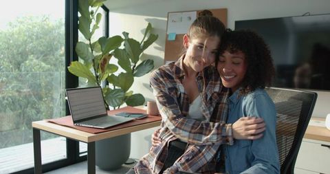 Diverse women embracing in modern home office setting