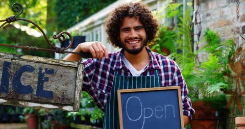 Smiling Gardener Welcoming Customers in Greenhouse - Download Free Stock Images Pikwizard.com