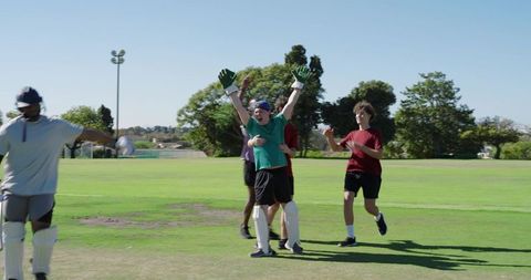Wicketkeeper celebrating victory with teammates on sunny cricket field