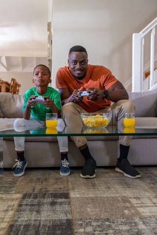 Black father and son gaming on living room couch