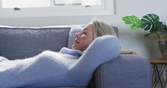 Relaxed senior caucasian woman in living room lying on sofa. retirement lifestyle, spending time at home.