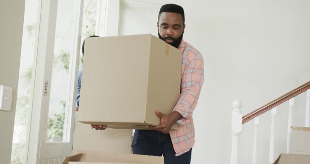 Busy african american couple moving house and holding cartons - Download Free Stock Photos Pikwizard.com