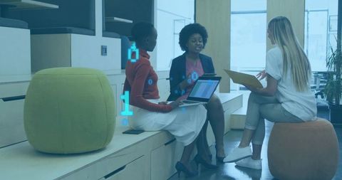 Three women collaborating in modern coworking lounge with laptops and documents