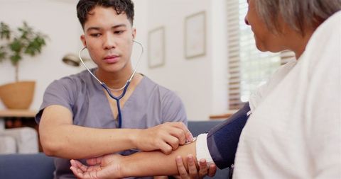 Young Male Physiotherapist Assisting Senior Woman's Health Exam