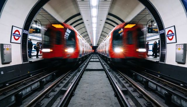 Passing red underground trains blurring through vaulted station platform roundel signs