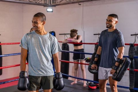 Young boxers training together in gym ring with teen girl leaning on ropes