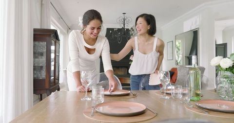 Women joyfully setting table for elegant home gathering