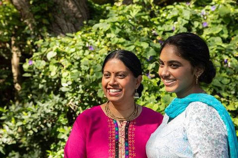 Smiling indian mother and daughter in vibrant traditional dresses
