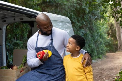 African american father and son selling fresh produce from van at outdoor farmers market