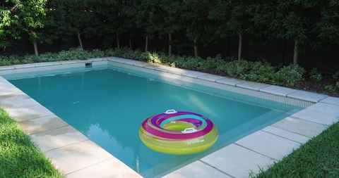 Inflatable pool ring floating in backyard swimming pool on sunny day