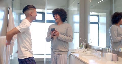 Diverse Friends Sharing Moment in Modern Bathroom While Checking Smartphone
