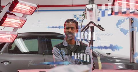 Automotive technician standing with arms crossed under infrared curing lights near car