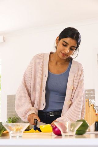 Woman cutting bell pepper in modern kitchen setting
