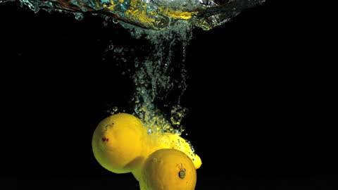 Fresh Lemons Splashing into Clear Water in Slow Motion