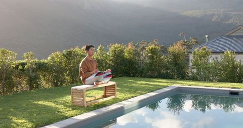 Man Meditating by Poolside in Nature with Paste Exercise Mat Alongside