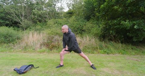 Athletic Man Stretching Outdoors in Park for Exercise Warm-up