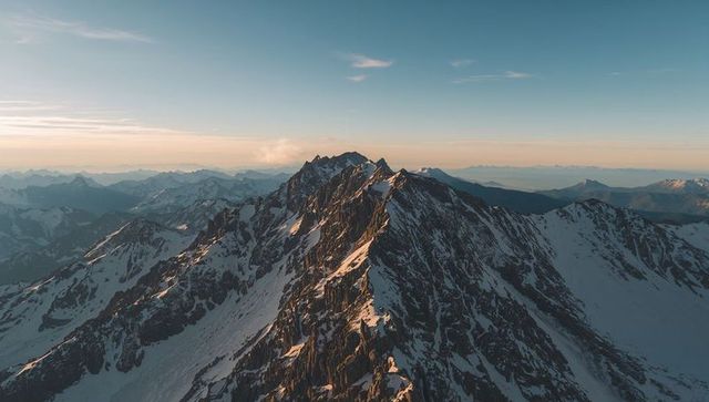 Golden sunrise on jagged snow-covered alpine ridge, high-altitude mountain panorama