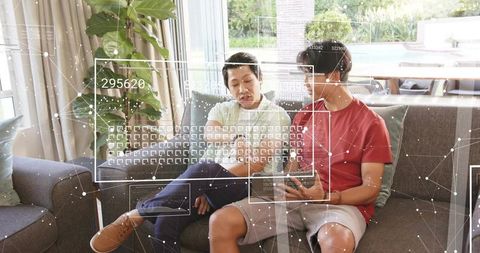 Father and teen son pointing at smartphone on sofa with ar hud overlays and living room