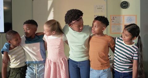 Elementary students standing together with arms around smiling in inclusive classroom