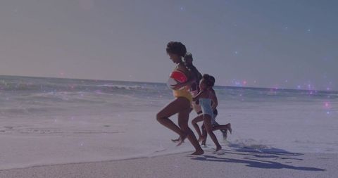 Family running toward ocean with inflatable ring on sunny beach, joyful summer activity