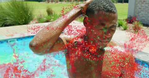 Shirtless man standing in backyard pool with vibrant color powder splash celebrating summer