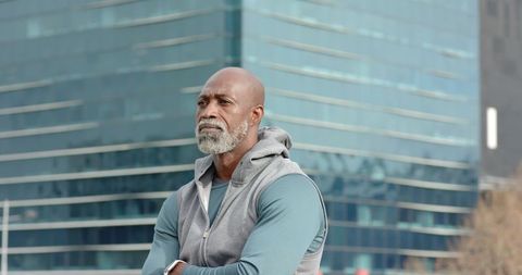 Mature African American man standing in urban plaza wearing sleeveless hoodie and smartwatch