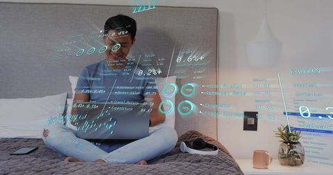 Man working on laptop in bedroom analyzing virtual financial dashboards for remote work