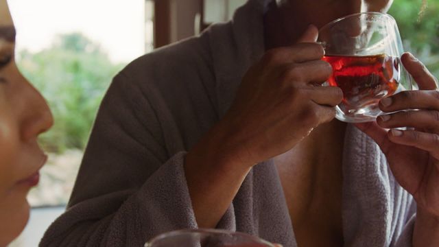 Middle-aged couple in bathrobes sharing a moment at a luxury health spa, drinking tea and enjoying each other's company. Ideal for concepts related to mindfulness, wellness retreats, and inclusive health lifestyles. Perfect for websites, brochures, or social media posts focused on spa experiences and peaceful retreats.