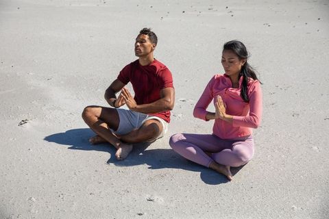 Couple Meditating on Beach in Bright Sunlight for Mindfulness and Peace
