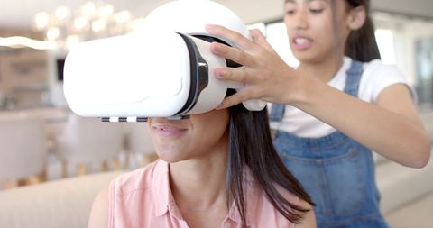 Teenage girl assisting friend with vr headset for virtual adventure