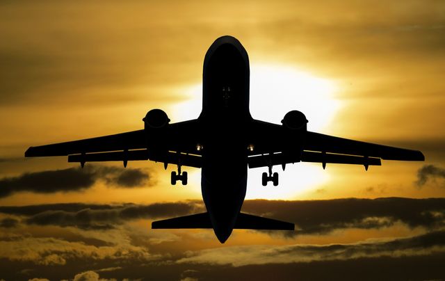 This striking image captures a commercial airplane silhouetted against the golden hues of a sunset sky, with the sun creating a dramatic backdrop. It is perfect for themes related to travel, aviation, adventure, commercial airline services, flight schedules, and vacations. The timelessness of the sunset setting makes it suitable for a range of promotional materials, advertisements, travel blogs, airline industry updates, and inspirational content about journeys and exploration.