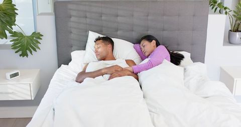 Middle-aged couple sleeping peacefully in modern minimalist bedroom, asian woman cuddling