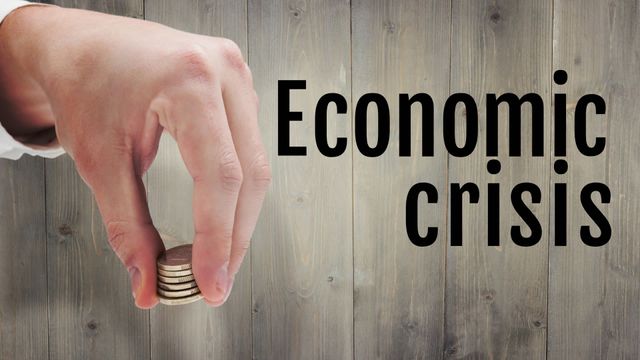 Image showing hand holding a few coins against a wooden background with 'Economic crisis' text overlay, reflecting financial instability. Suitable for financial articles, economic reports, savings guides, financial advice blogs, illustrating economic struggles.