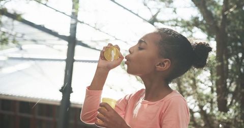 Young African American Girl Blowing Bubbles Outdoors on School Playground