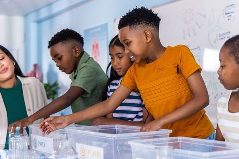 Elementary students sorting recyclables in classroom recycling activity promoting teamwork