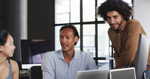 Diverse colleagues collaborating around computer in modern office